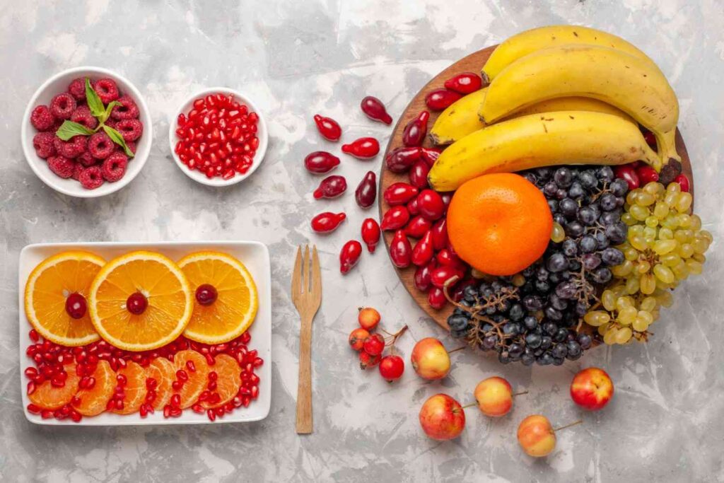Fresh fruits including oranges, grapes, bananas, raspberries, and pomegranate that support healthy blood circulation.
