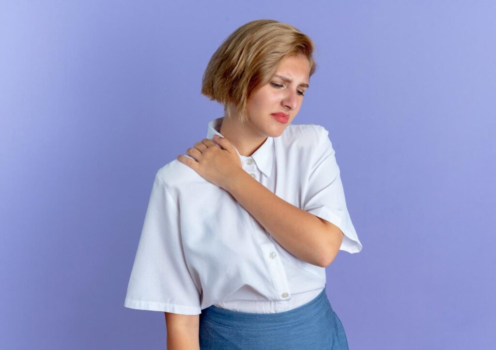 Woman experiencing collarbone pain near the left shoulder and clavicle.
