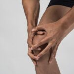 Person holding painful knee showing possible gout in knee symptoms