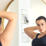 Woman checking armpit fat and underarm area in mirror