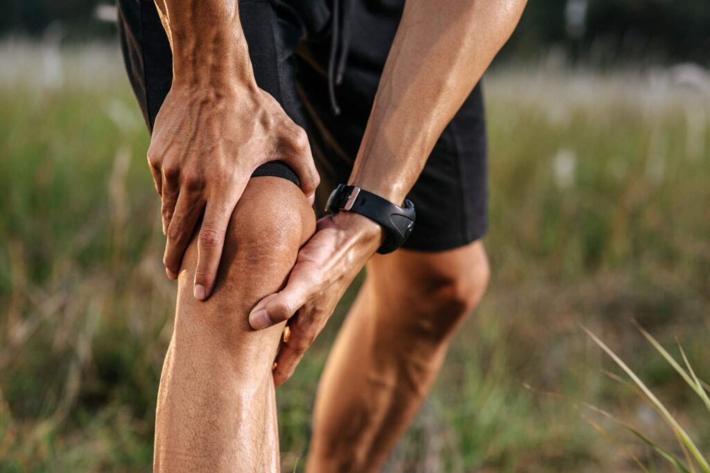 Person holding knee due to pain and inflammation related to possible gout symptoms