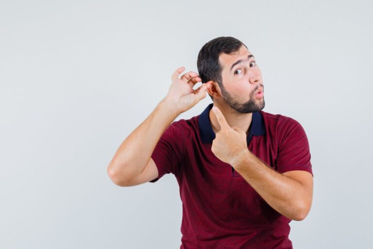 Man pointing at a painful pimple in his ear showing ear pain and discomfort.